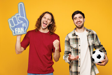 Young winner two friends men sport fans in casual clothes foam 1 fan glove finger up cheer up...