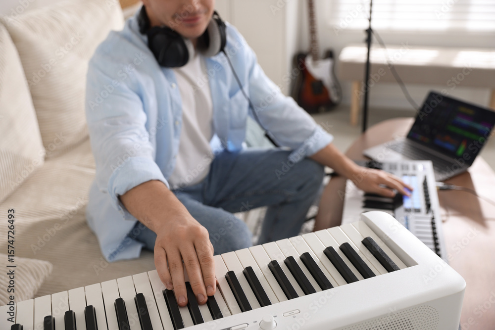 Poster man working with digital piano and midi keyboard in home studio, selective focus