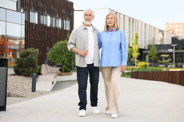 Lovely senior couple walking together on city street