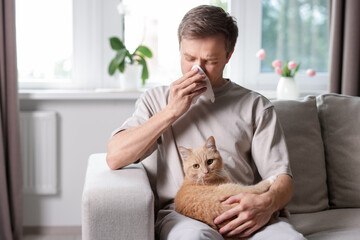 Man suffering from allergy with his cat on sofa at home