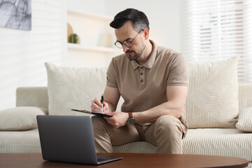 Professional psychologist having online consultation with his client via laptop on sofa indoors