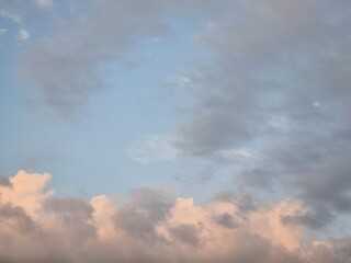 Bright fluffy white clouds floating across a clear blue sky on a sunny afternoon