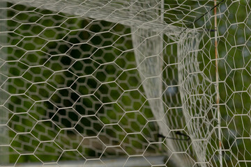 The closeup image of the soccer goal net shows its hexagonal mesh structure against a vibrant green...