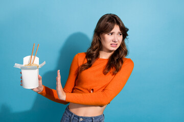 Young woman in casual orange sweater portraying animated expressions against aqua blue background