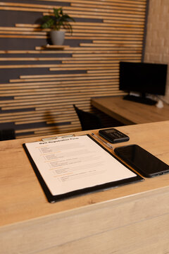 Clipboard holding gym registration form sitting on reception desk amid pen, plant, slat wall