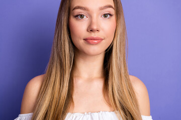 Stylish young woman with long blonde hair posing in casual white top against a violet background...