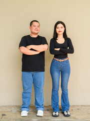 Full length portrait of young couple against plain wall background