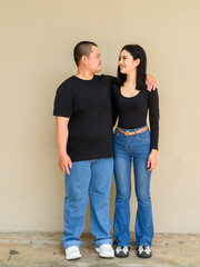 Full length portrait of young couple against plain wall background