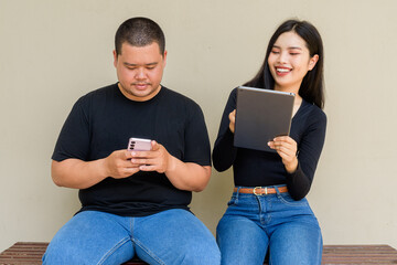 Portrait of young couple against plain wall background using tablet computer