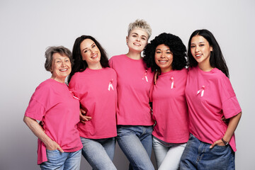 Diverse women wearing pink ribbons are embracing for breast cancer awareness