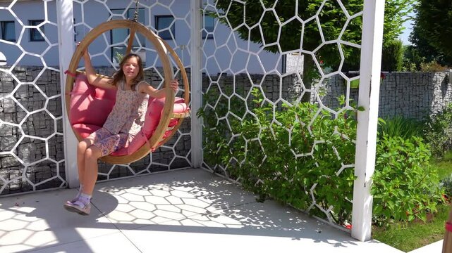 Slow Motion Teen girl swinging on a soft swing in a beautiful city park.