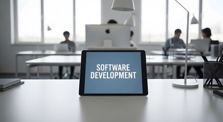 Modern Office Workspace showcasing Software Development on a tablet. Blurred background depicts colleagues working diligently at their desks, illustrating a collaborative environment.