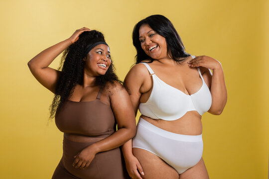 Diverse plus-size female friends standing in studio modeling brown and white bras and briefs