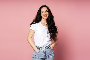 Beautiful smiling woman with long curly hair posing on pink background