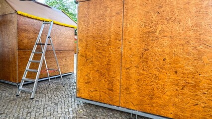 Ladders lean in silent conspiracy beside plywood stalls, whispering tales of Oktoberfest...