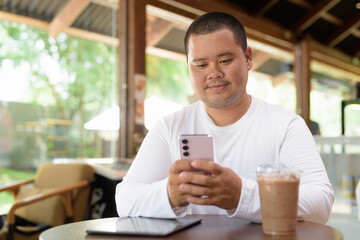Asian plus size happy man sitting in cafe restaurant