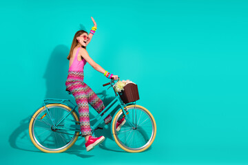 Energetic woman riding a teal bicycle against a vibrant turquoise background, showing youthful...