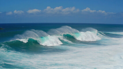 Ocean waves crashing under a clear blue sky with some clouds, creating a dynamic and refreshing scene.