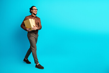 Confident young professional man with files walking on a bright teal background, showcasing office...