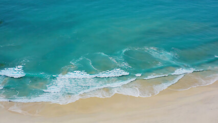 Aerial view of a beautiful beach with turquoise water and gentle waves washing onto the sandy shore.