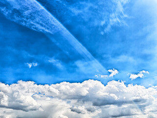 The bright blue expanse of the sky, dotted with fluffy, scattered clouds, beautifully highlights a...