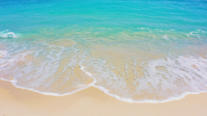 Aerial view of a serene beach with turquoise water and soft sand.