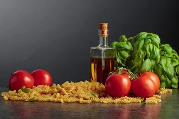  Fusilli pasta with olive oil, tomatoes and basil on a black background. © Igor Normann