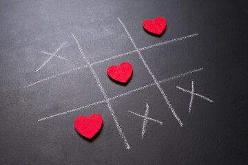 Close up of Tic-tac-toe game with red hearts on blackboard representing World Heart Day