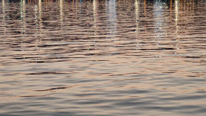 Coastal evening lights reflecting in sea water, blurred water background
