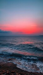 Vibrant Ocean Sunset with Waves Crashing on a Rocky Shore