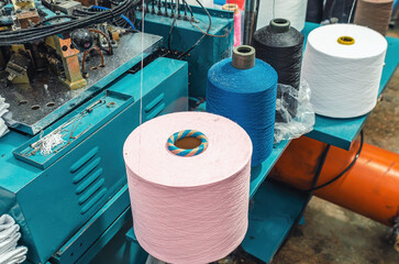 Top view of colored threads on spools on machines. Industrial enterprise for production of socks....