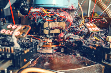 Knitting machine with yarn dust. Close-up of knitting machine with cotton yarn in a sock factory.