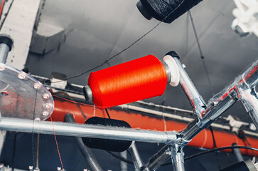 Bottom view of colored threads on spools on machines. Industrial enterprise for production of...