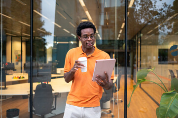Businessman drinking coffee and reading tablet outside office