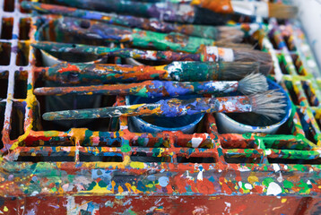 Konzept Kunst, Malen und Farbe: Authentisch mit Farbe bedeckte Pinsel auf einem farbverschmierten...