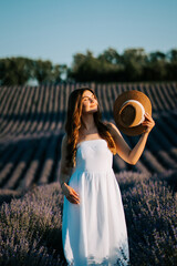 Woman in white dress enjoying lavender field during golden hour in summer sun