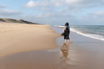 A woman walking barefoot on the sand of the Landes. Cap de l'Homy beach in Lit et Mixe.