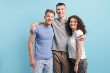 Three friends hugging on light blue background