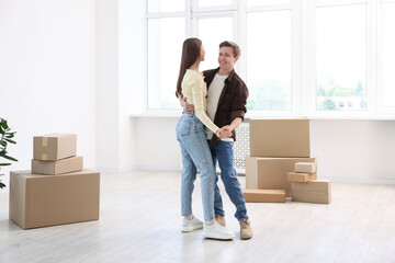 Happy young couple dancing among moving boxes at home