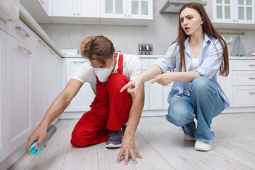 Worried woman and pest control worker spraying insecticide at home