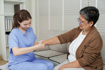 Senior asian woman undergoing physical arm therapy with female therapist stretching arm slowly...