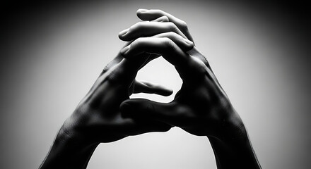 Two hands interlaced, forming a triangular shape against a gradient backdrop in a black and white studio shot.