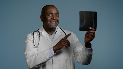 Pensive smiling African American man male radiologist doctor surgeon traumatologist examining x-ray...