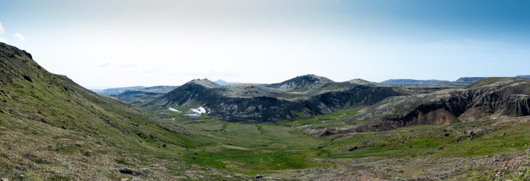View of a lush green valley dotted with volcanic hills and steaming vents under a clear blue sky, a serene landscape, Hverager&Atilde;&deg;i, Sveitarf&Atilde;&copy;lagi&Atilde;&deg; &Atilde;&ndash;lfus, Iceland.