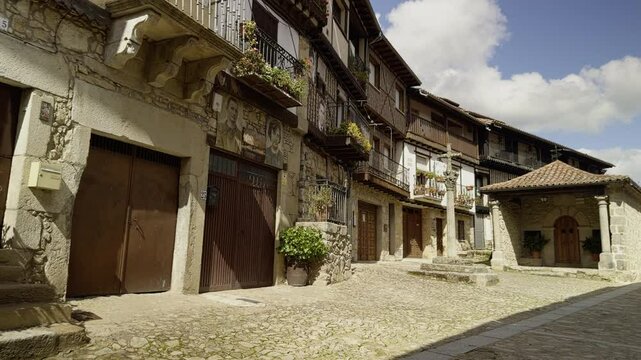 Sunlit street in Mogarraz, famed for portraits on fa&ccedil;ades and rustic architecture. Great for cultural, travel, and heritage visuals.