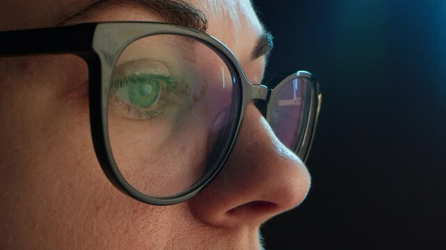 Close up of tired woman working at night on laptop, girl in eye glasses with reflections overworking busy, using computer in dark office