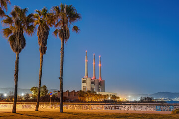 The shutdown thermal power station and three palm trees at Sant Adria near Barcelona at twilight