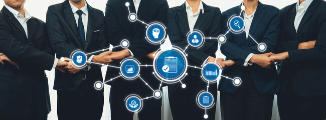 A group of business professionals in suits stands together, showcasing diverse technology icons and...