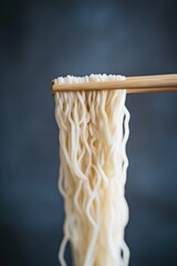 A pair of chopsticks picking up noodles or ramen. Holding noodle with chopsticks. chopsticks to pick up neatly long noodles in the air. 