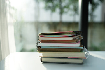 Stack of Old notebooks on white desk by the window